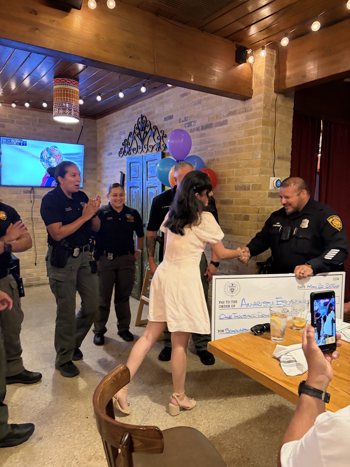 Scholarship recipient shaking hands with an SAPD officer as the room applauds
