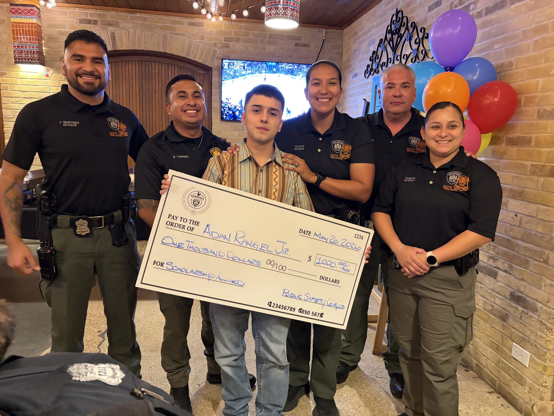 Scholarship recipient Adan Rangel Jr. holding his $1,000 Public Safety Corps award check with Explorer advisors