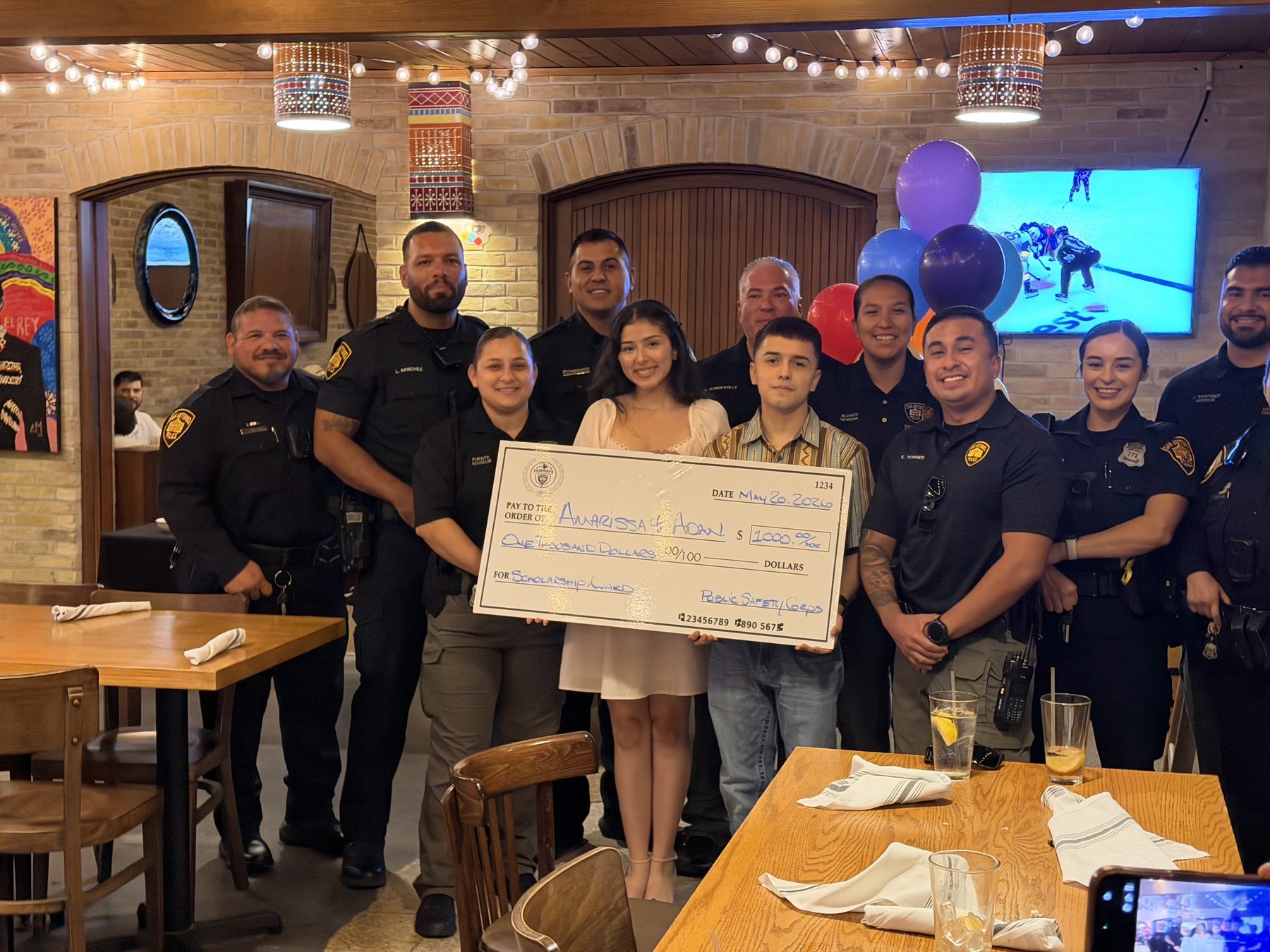 SAPD officers and Explorer advisors with the two scholarship recipients holding a $1,000 Public Safety Corps award check